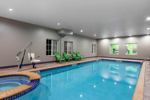 a pool in a hotel room with green chairs and a swimming pool at La Quinta by Wyndham Huntsville Airport Madison in Madison