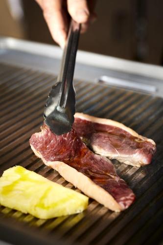 a person cooking meat on a grill with a fork at Alcazar Hotel & SPA in Monte Gordo