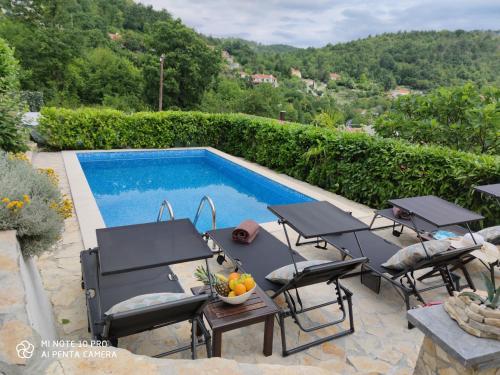 a swimming pool with tables and chairs next to at Apartment Gina in Opatija