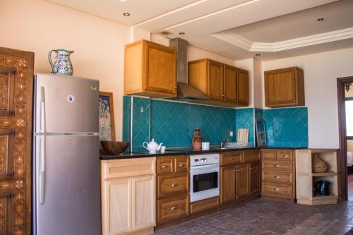 a kitchen with wooden cabinets and a refrigerator at Imsouane Surf Paradise in Imsouane