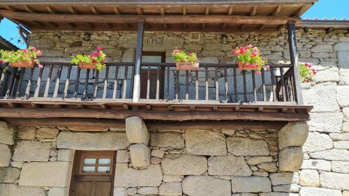 a stone building with potted plants on a balcony at Casa Garcia - Chaves in Chaves
