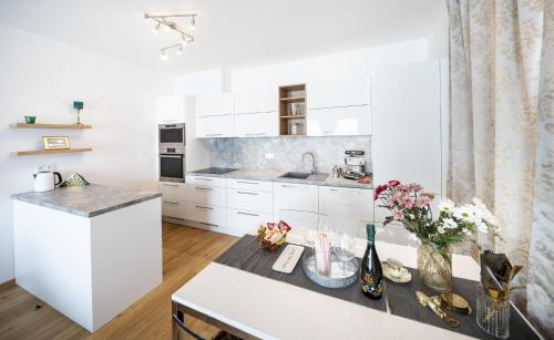 a kitchen with white cabinets and a counter with flowers at Silvie Apartments - Zlaté Terasy in Olomouc