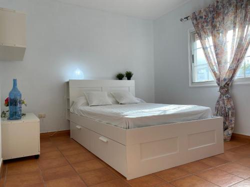 Un dormitorio con una cama blanca y una ventana. en Casa Mariet, en La Hidalga
