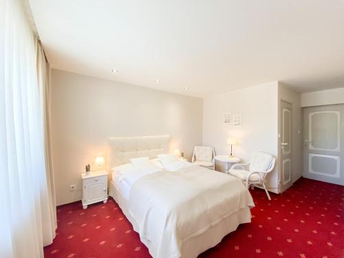 a bedroom with a large white bed and two chairs at Willa Mandala in Dziwnówek