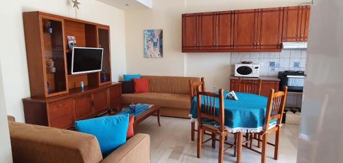 a living room with a couch and a table and chairs at Holiday Dream Aphrodite Apartment in Mastihari
