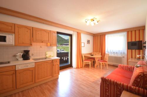 a kitchen with wooden cabinets and a dining room with a table at Sonnenhof Walchsee in Walchsee