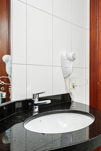 a bathroom sink with a phone on a counter at Firenze Business Hotel in Palhoça