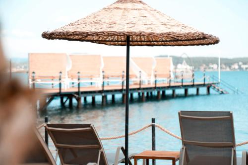 a table and chairs with an umbrella and a pier at Cunda Fora Glamping in Ayvalık