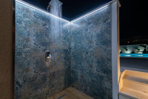 a bathroom with a shower with a stone wall at Apartments Vrania in Seget Vranjica