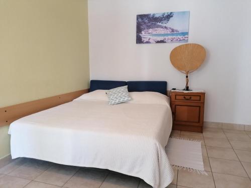 a bedroom with a white bed and a wooden nightstand at Apartments Tonka in Mošćenička Draga