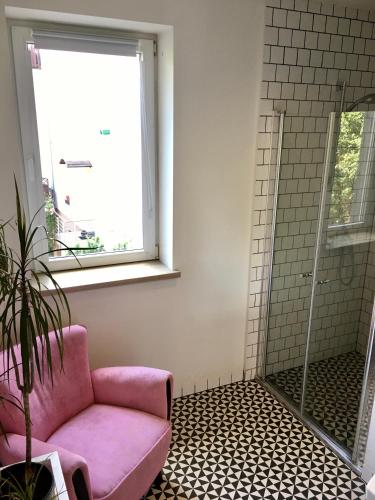 a bathroom with a pink chair and a shower at SPOKO Hostel in Gdańsk