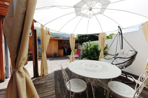a patio with a table and chairs and an umbrella at Le VISCOS à AGOS-VIDALOS in Agos-Vidalos