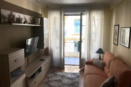 ein Wohnzimmer mit einem Sofa und einem TV in der Unterkunft Joli 2 pièces à 150m de la plage in Nizza