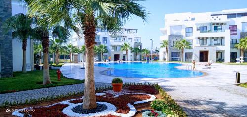 ein Pool mit Palmen und ein Gebäude in der Unterkunft Hivernage Founty in Agadir