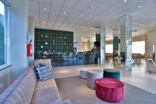 a lobby with a couch and two stools at Executive Inn Fernandopolis in Fernandópolis