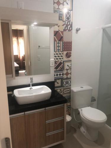 Un baño con inodoro, lavabo y espejo. en Apto Piratuba Termas, en Piratuba