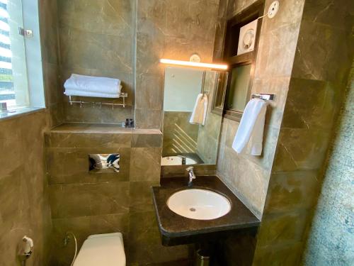 a bathroom with a sink and a toilet and a mirror at Ace Iconic in Greater Noida