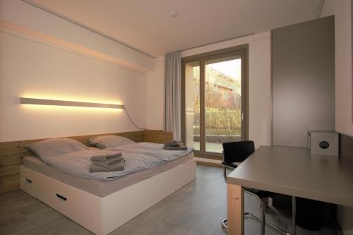 a bedroom with a bed with a desk and a window at Campus Apartments in Göttingen