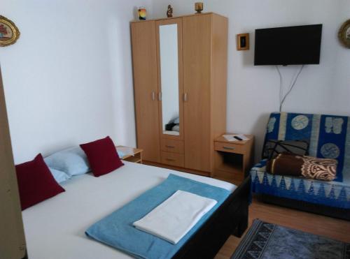 1 dormitorio con 1 cama, TV y silla en Apartmani Vrzić, en Baška