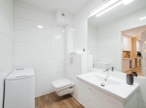 a white bathroom with a toilet and a sink at Nadmorskie Tarasy Apartament #PORTY B103 in Kołobrzeg