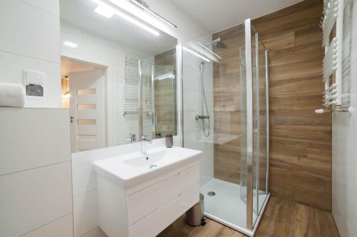 a white bathroom with a sink and a shower at PORTY b103 Nadmorskie Tarasy pool sauna parking in Kołobrzeg