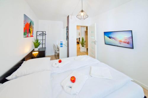 a white bedroom with a bed with two red apples on it at PORTY b103 Nadmorskie Tarasy pool sauna parking in Kołobrzeg