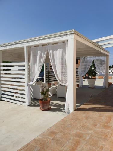 een witte pergola met witte gordijnen op een patio bij Casa Vacanze Luxury CASELLO 28 in Marconia