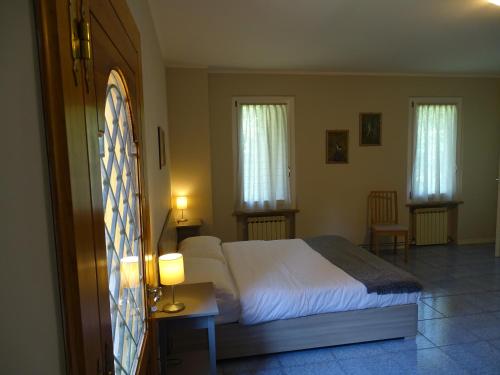 a bedroom with a large bed and two windows at Corte Isolo in Goito