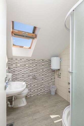 a bathroom with a sink and a toilet and a window at Country House Pansion in Cavtat