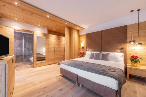 a bedroom with a large bed and a bathroom at Hotel Meida in Pozza di Fassa