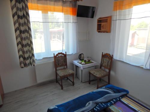 a bedroom with two chairs and a table and two windows at Villa Orkan in Grzybowo