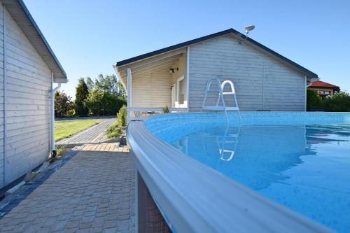 a swimming pool in front of a house at Pogodne Domki in Darłowo