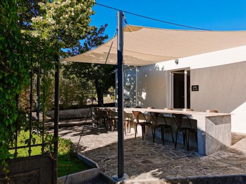 un patio con mesa y sillas bajo una sombrilla blanca en Maison San Giovanni en Corte