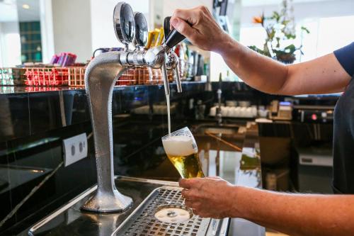 a man drinking a beer from a faucet at Executive Inn Fernandopolis in Fernandópolis