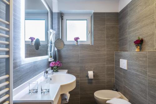 a bathroom with a sink and a toilet and windows at Hotel Meida in Pozza di Fassa