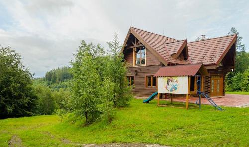 a wooden house with a playground in front of it at ZRUB BINDT in Hnilčík