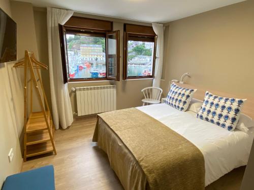 Schlafzimmer mit einem Bett mit blauen und weißen Kissen in der Unterkunft Hotel Baltico 2 estrellas in Luarca