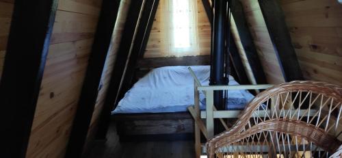 a bed in a wooden cabin with two wicker chairs at Zelenaya Usad`ba StavBor in Zavadivka