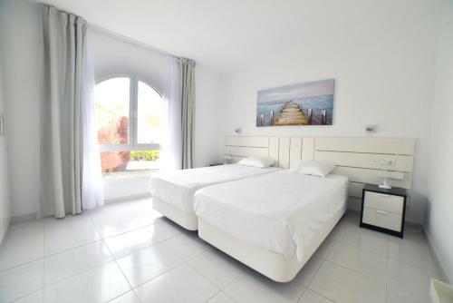 a white bedroom with a white bed and a window at Casa Roja in Costa Calma