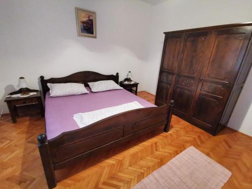 Un dormitorio con una gran cama de madera con sábanas moradas. en Apartments Plejic, en Seget Vranjica
