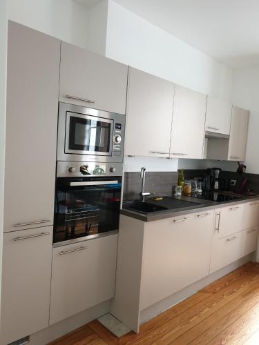 une cuisine avec des armoires blanches et un micro-ondes dans l'établissement le castor, à Deauville