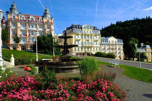 a large building with a fountain and flowers in front of it at Apartment Anglicka 138 in Mariánské Lázně