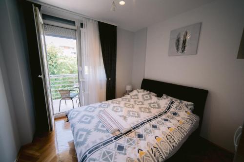 - une chambre avec un lit et une fenêtre avec un balcon dans l'établissement Apartment LIPA, à Novi Sad