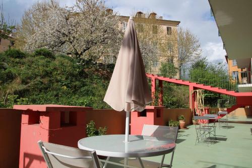 ein Regenschirm auf einem Tisch auf einer Terrasse in der Unterkunft Hôtel Sampiero Corso in Corte