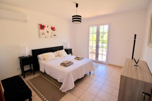 - une chambre avec un lit doté de draps blancs et d'une croix dans l'établissement Domaine de l'oasis, aux Arcs-sur-Argens