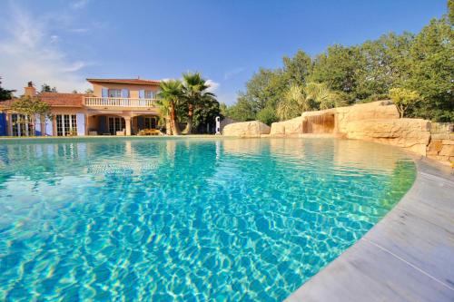 une piscine avec de l'eau bleue devant une maison dans l'établissement Domaine de l'oasis, aux Arcs-sur-Argens