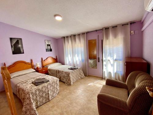 a hotel room with two beds and a chair at APARTAMENTO TURISTICO NAVALINDA in Casas del Monte