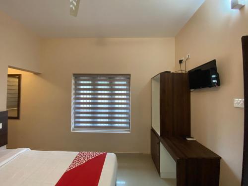 a bedroom with a bed and a window at La Mer Inn in Kozhikode