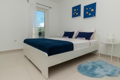 Un dormitorio blanco con una cama grande con una manta azul. en Čikat bay residence, en Mali Lošinj