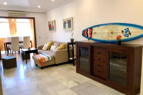 ein Wohnzimmer mit einem großen Surfbrett auf einer Kommode in der Unterkunft GATU Villa Buena Vida , aire acc y wifi in El Puerto de Santa María